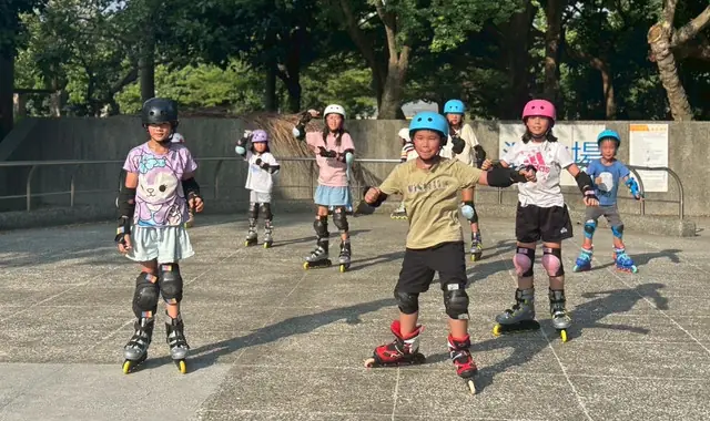 孩子們穿著直排輪鞋與護具,在溜冰場排成一列